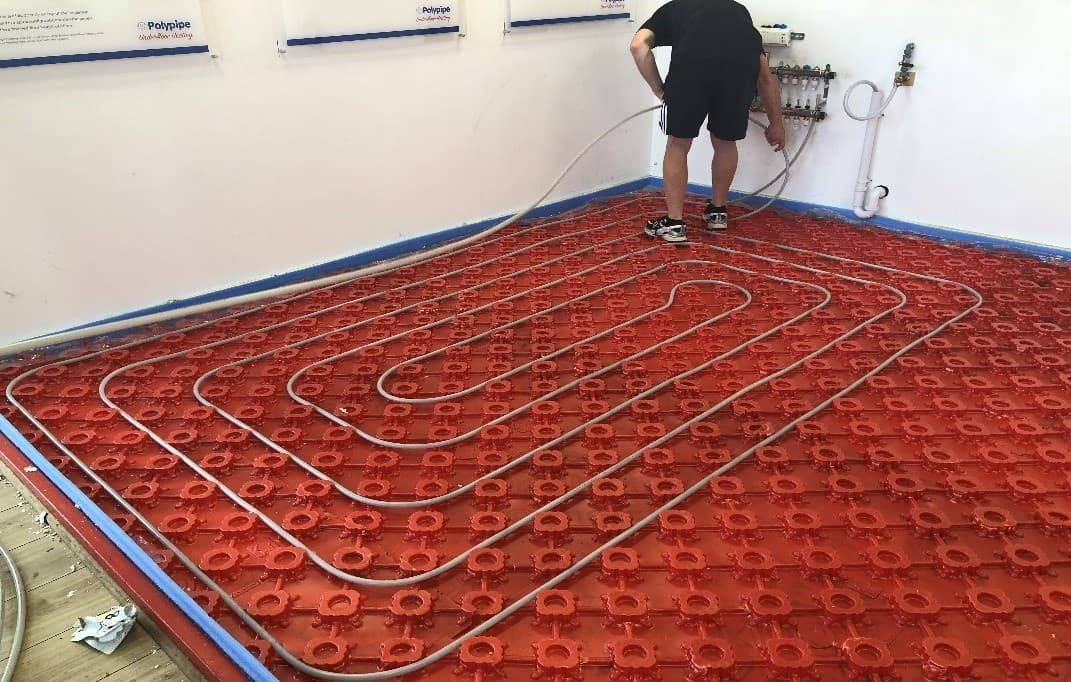 An installer lays underfloor heating pipe at the Polypipe Professional Development centre.
