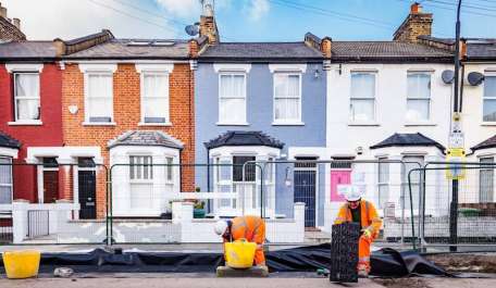 Polypipe workmen working in front of colourful houses installing a retrofit SuDS solution.